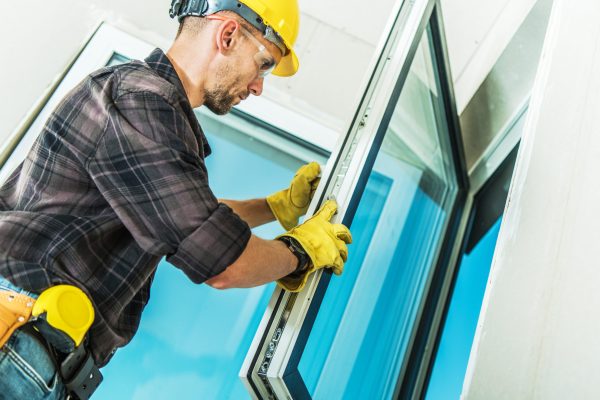Caucasian Middle Aged Professional Contractor Checking Locks and Handle Assembly During Windows Installation Process in Freshly Built Residential House.