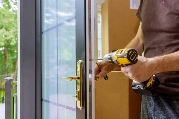Install the door handle with a lock, Carpenter tighten the screw, using an electric drill screwdriver, close-up.